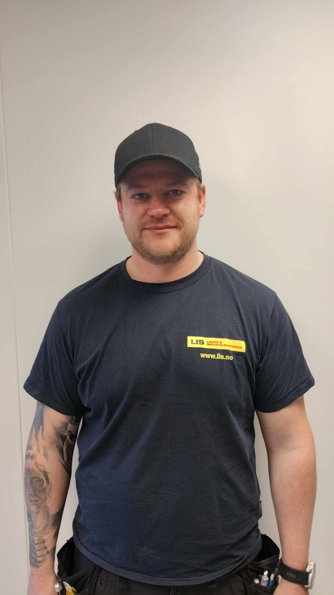 Sort-hexagonalt portrett av en mann med hettegenser fra LIS Solutions, smilende vennlig mot kameraet.