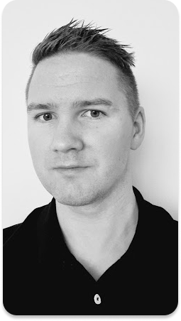  Et portrett av en mann med en seriøs uttrykk i et sekskantet format. Han har kort, lyst hår, en renbarbert ansikt, og bærer en svart overdel. Bildet er i svart-hvitt og fremstår som profesjonelt og nøytralt.